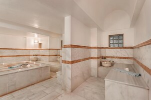A bathroom with a marble vanity, a bathtub, and a window.