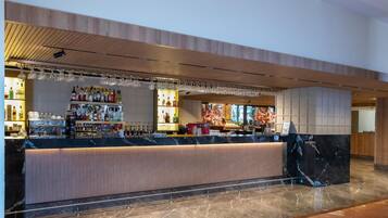 A modern bar area with a marble countertop, a wooden ceiling, and a tiled floor.