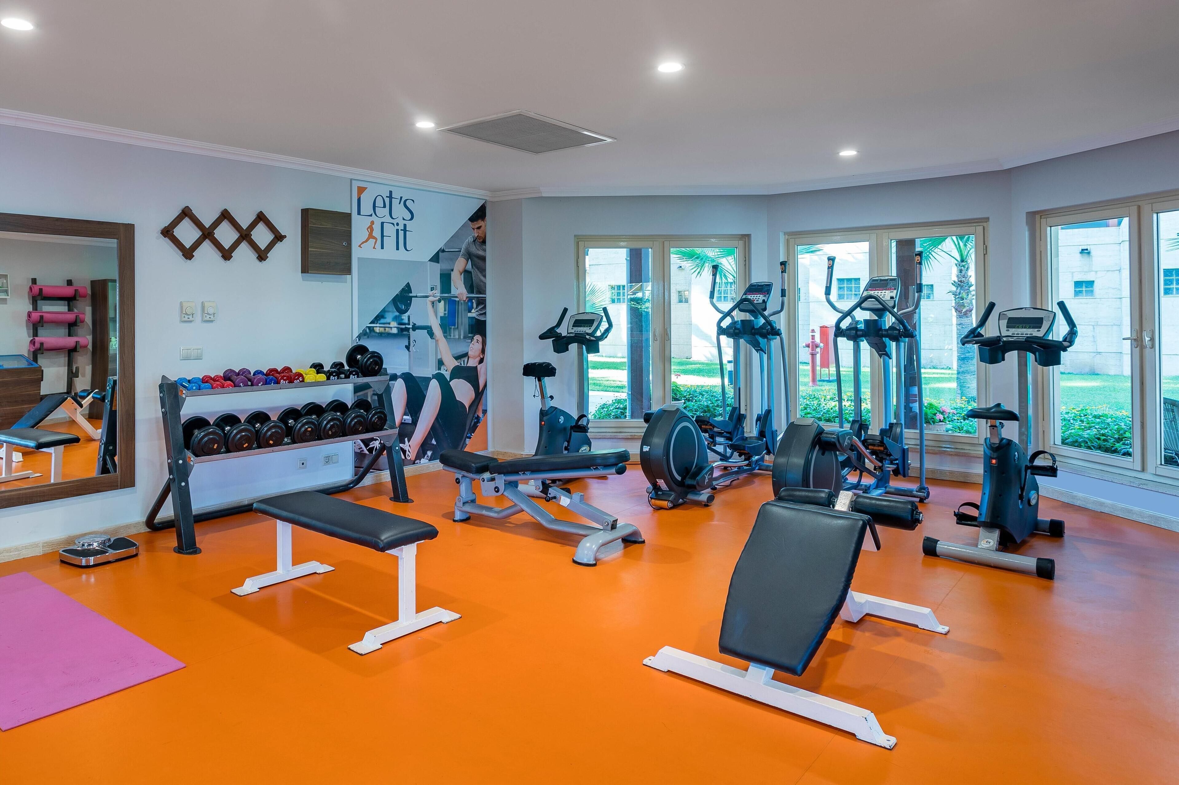 A gym with various exercise equipment, a mirror, and a wall with motivational text.