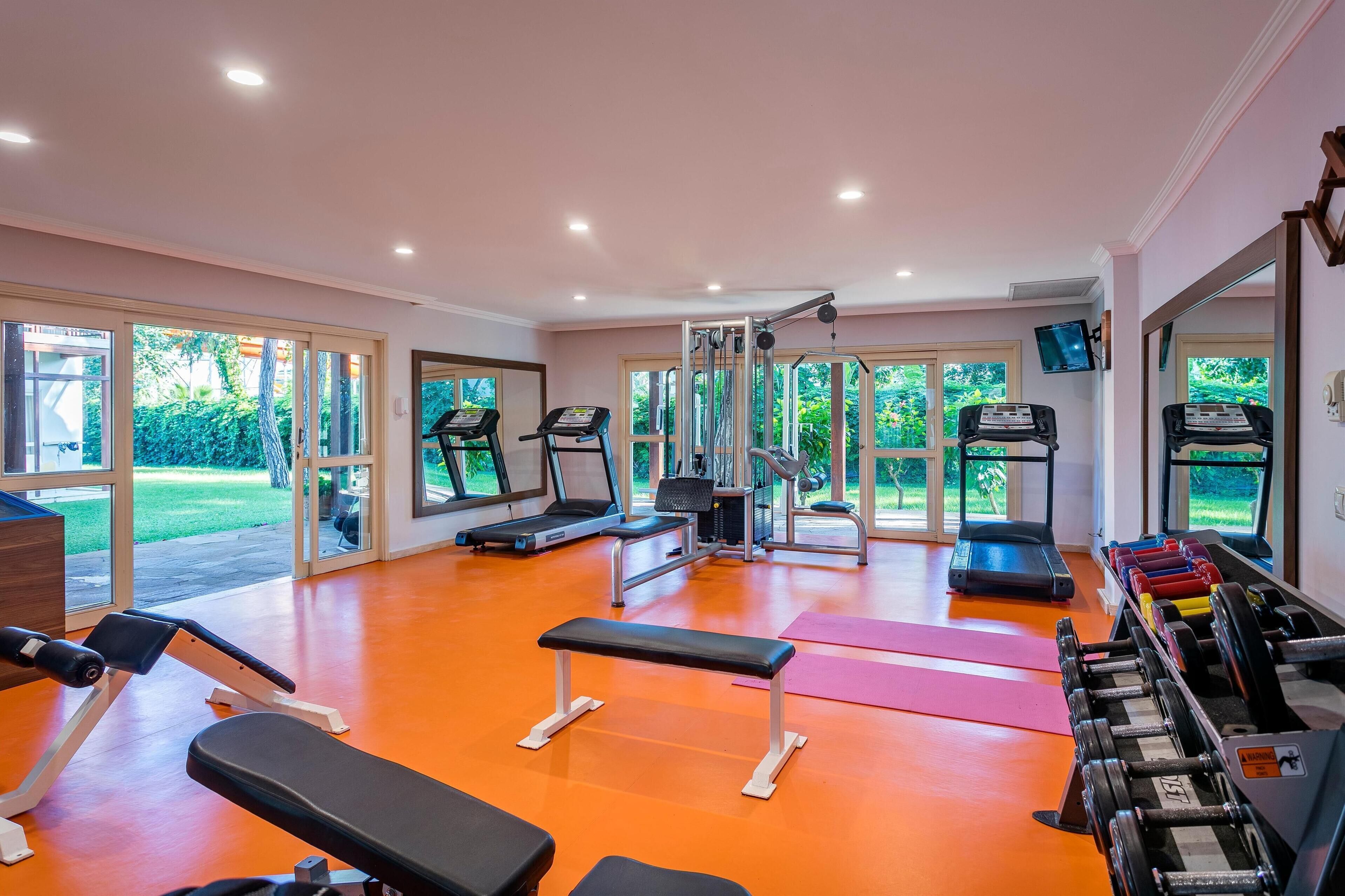 A gym with treadmills, weight machines, and a bench.