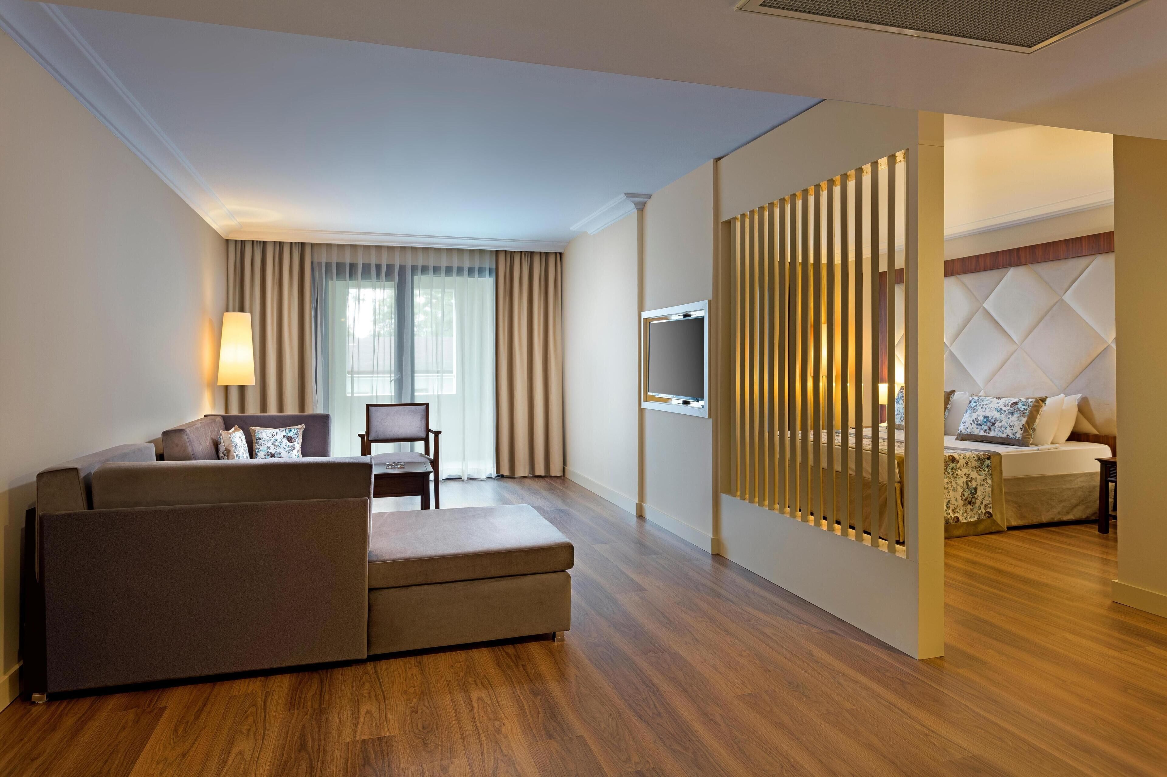 A modern hotel room with a sofa, a television, and a bed with a headboard.