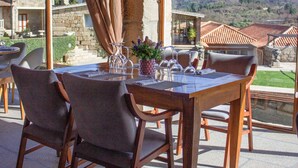 Un coin repas avec une table dressée pour deux personnes, de grandes fenêtres et une vue sur un paysage montagneux.