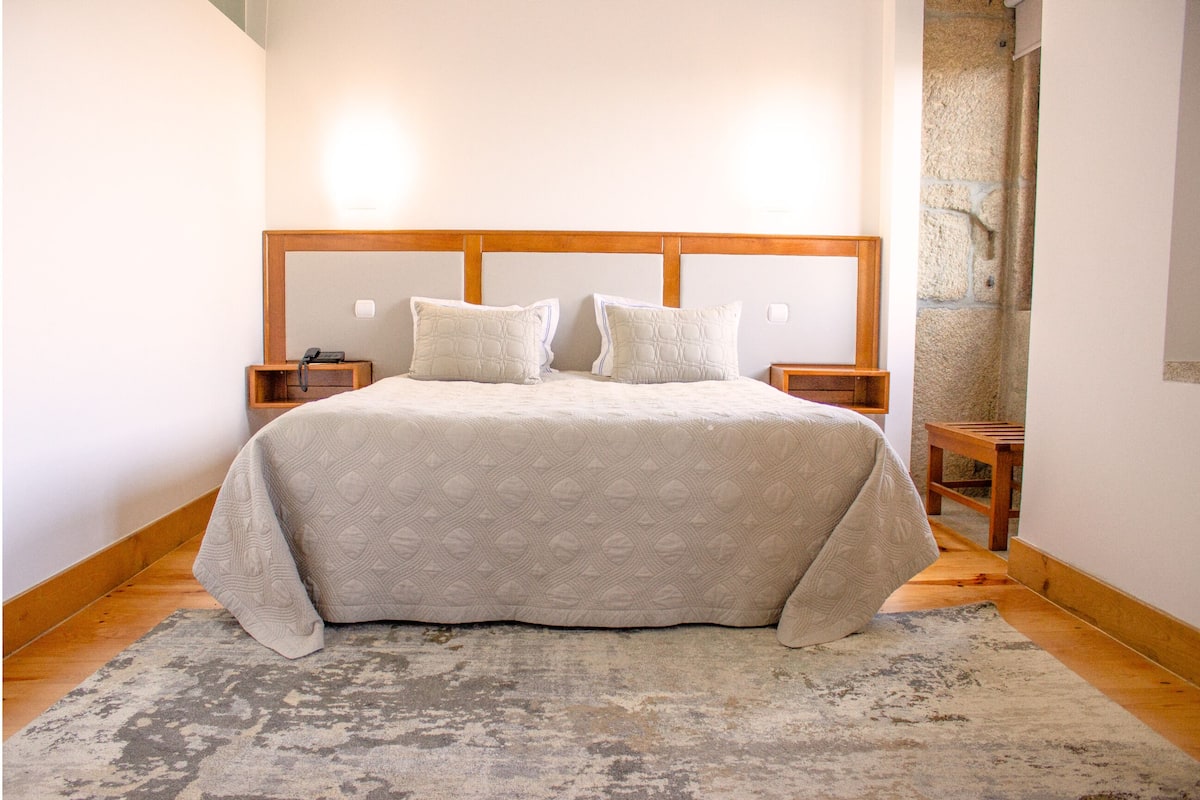 A bed with a wooden headboard, two bedside tables, and a patterned bedspread.