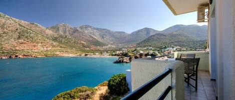 A balcony with a view of a coastal landscape, including mountains and a body of water.