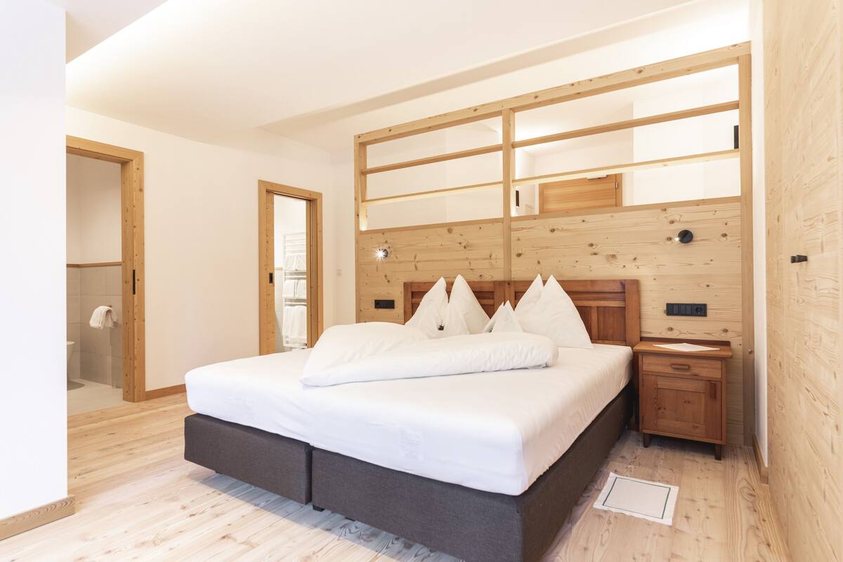 A bedroom with a large bed, wooden headboard, bedside tables, and a wooden wardrobe.
