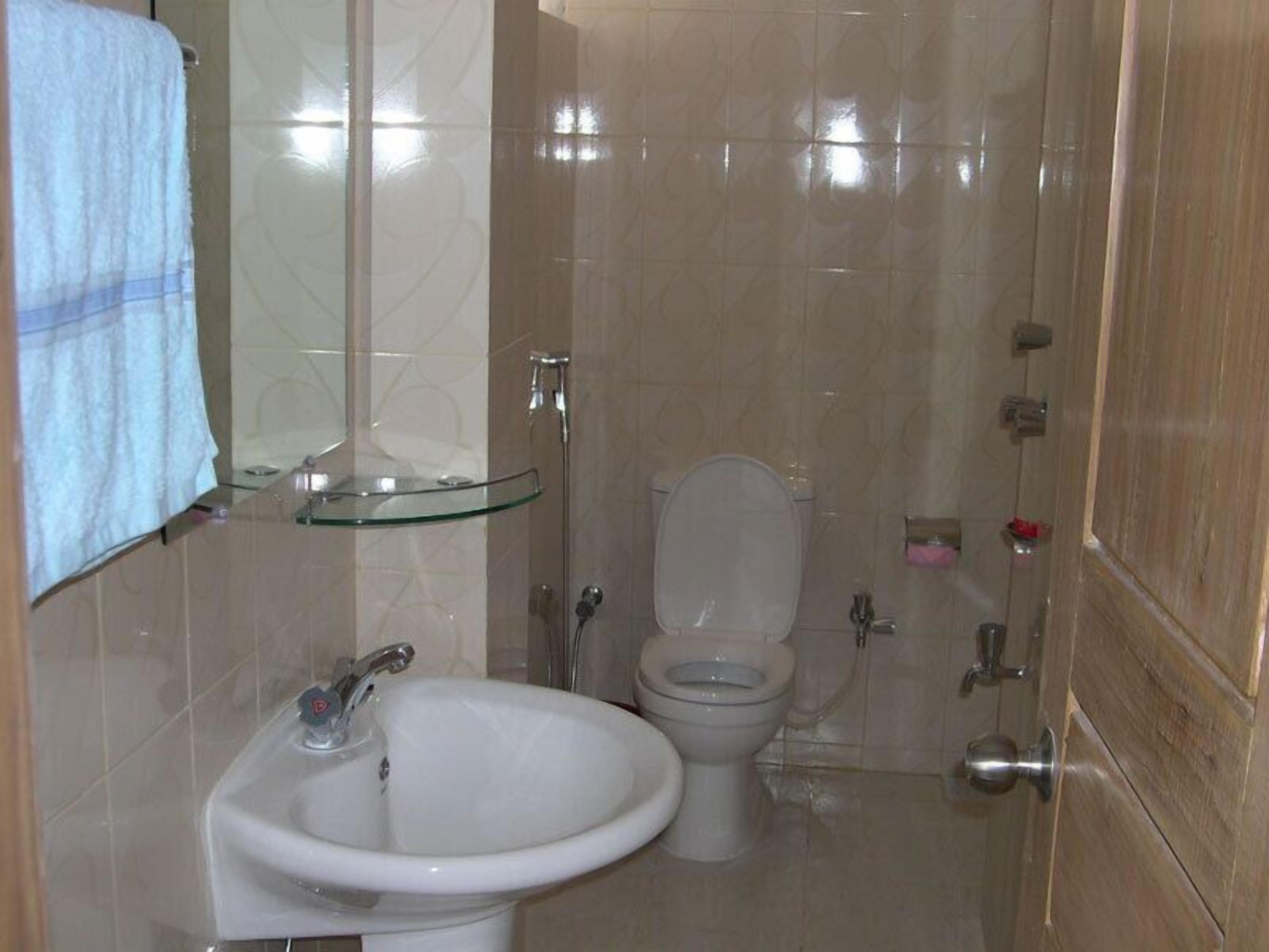 Ein Badezimmer mit Duschkabine aus Glas, einem weißen Waschbecken und einer Toilette.