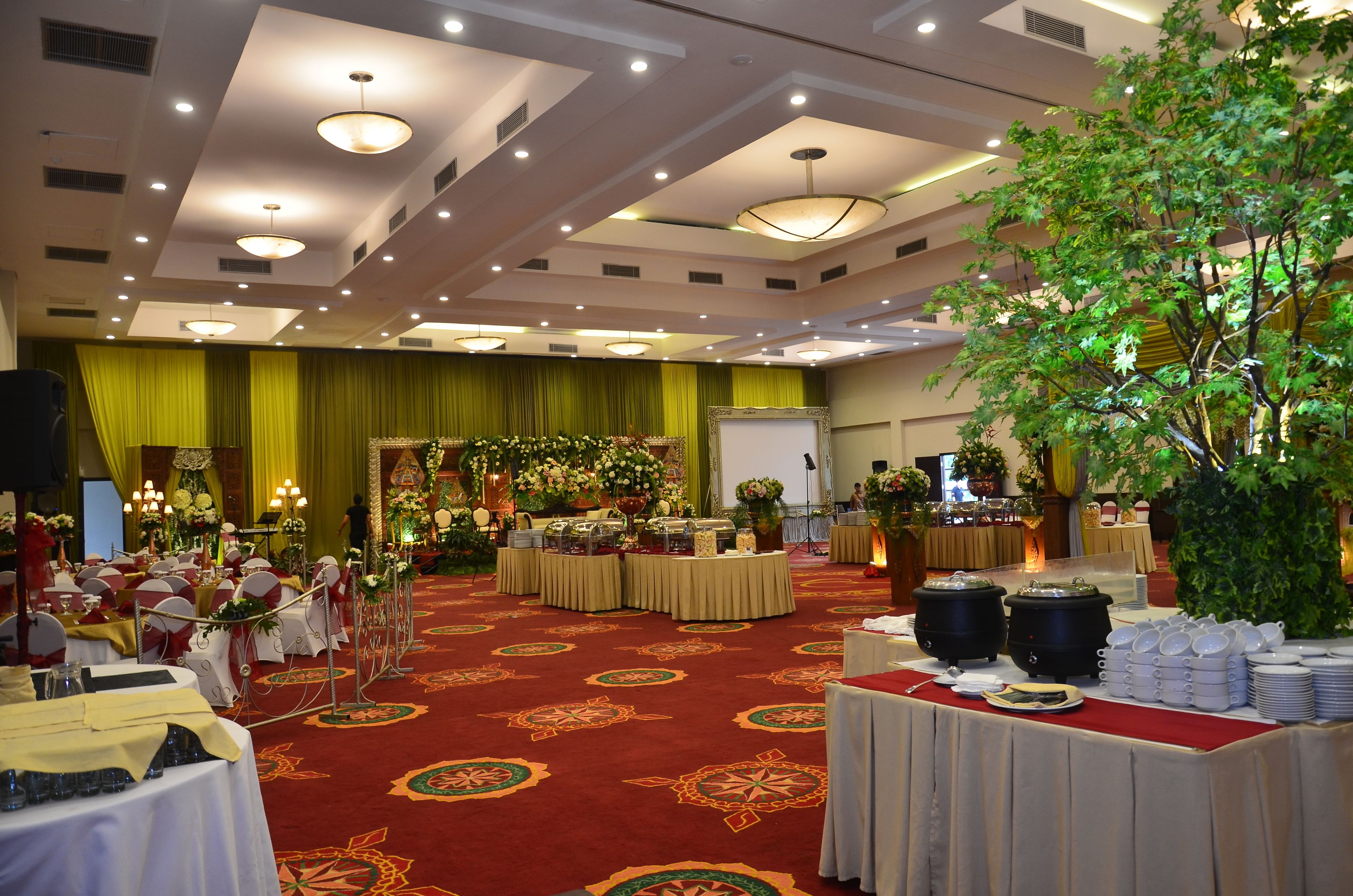 A banquet hall with round tables, floral centerpieces, and a stage.