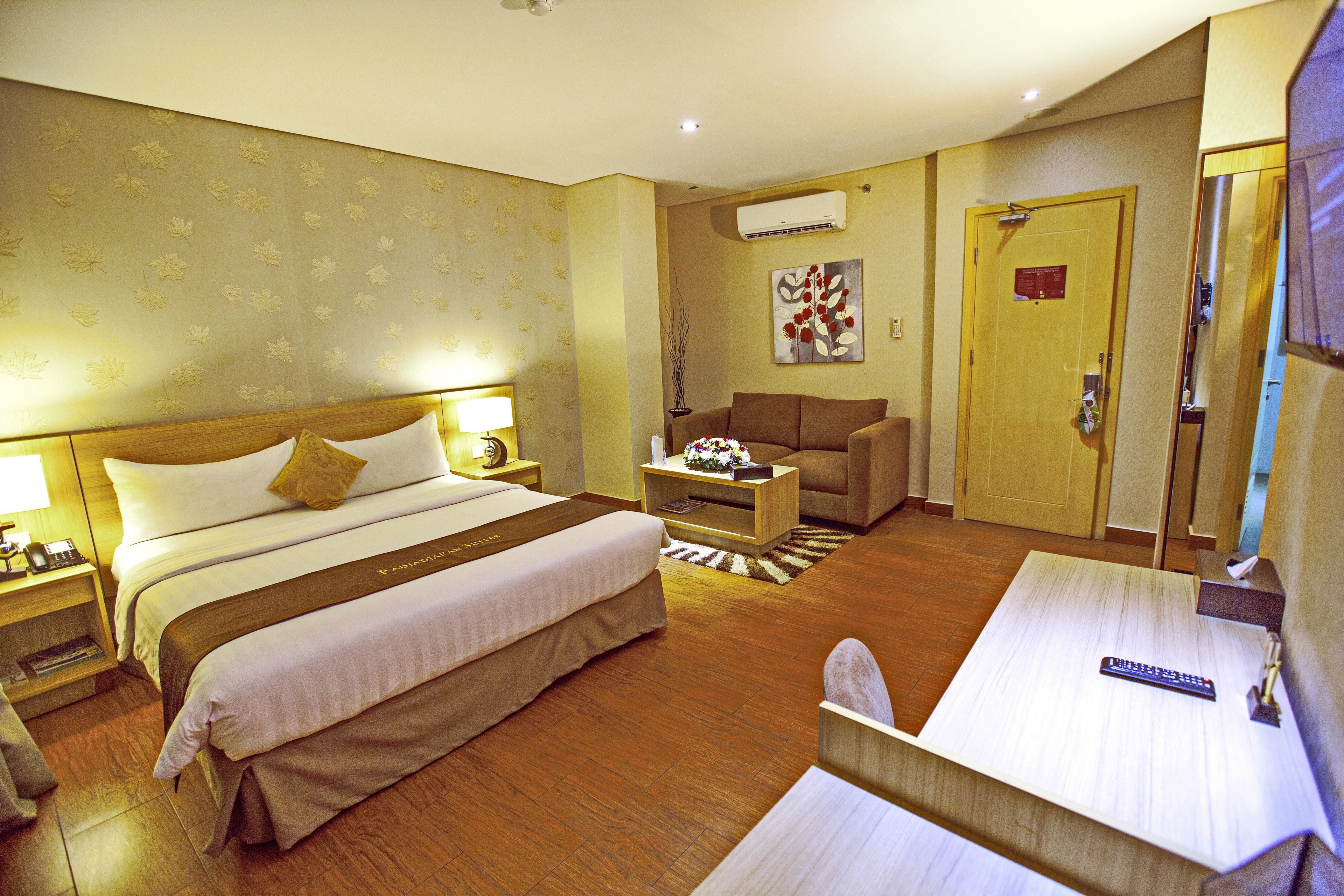 A hotel room with a large bed, a sofa, a small table, and a TV.