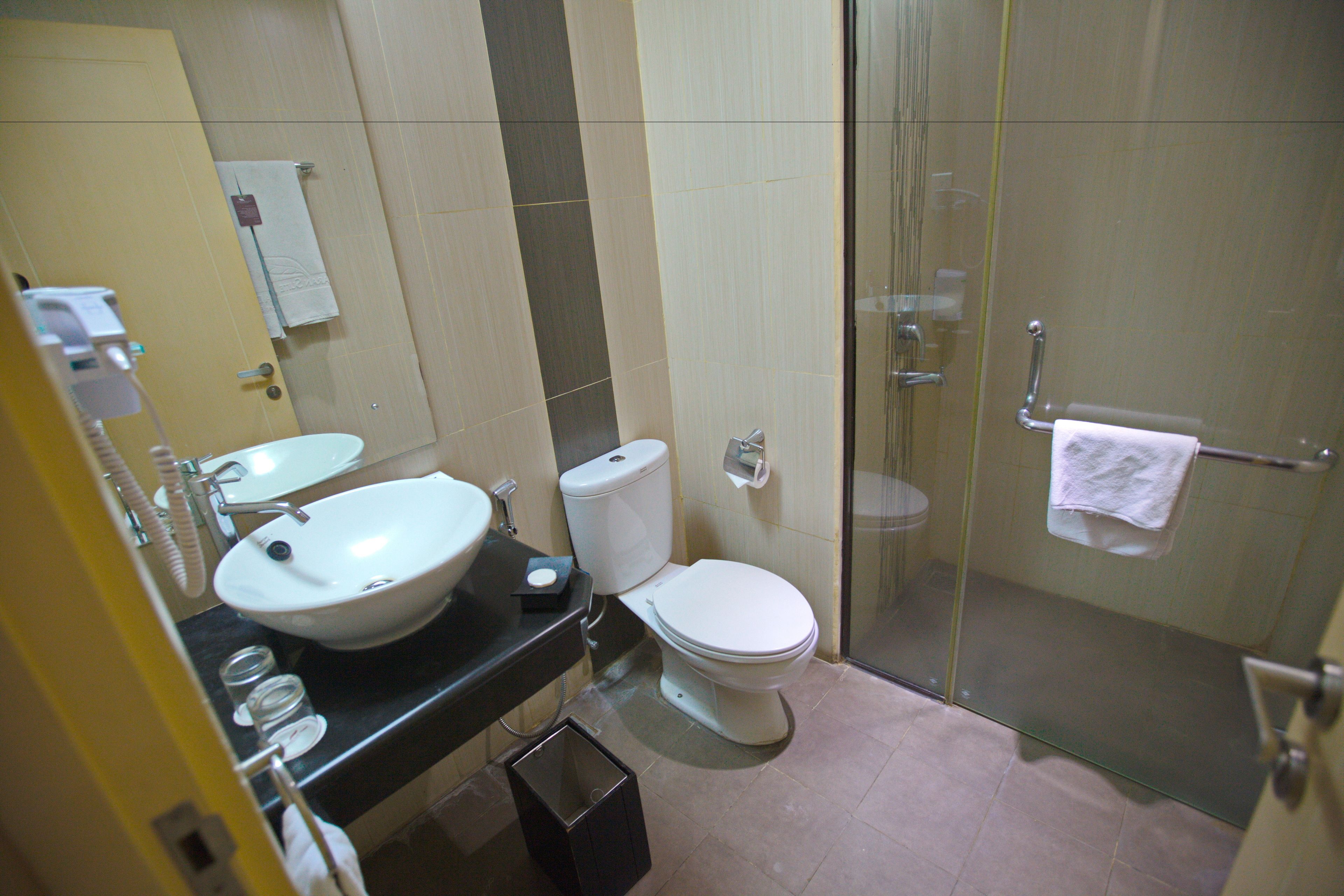 Un baño con lavamanos, inodoro y ducha con mampara de vidrio.