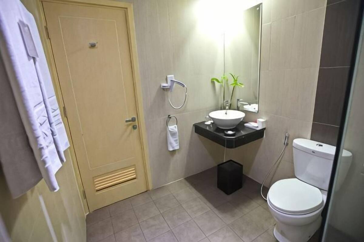 A bathroom with a toilet, sink, and mirror.
