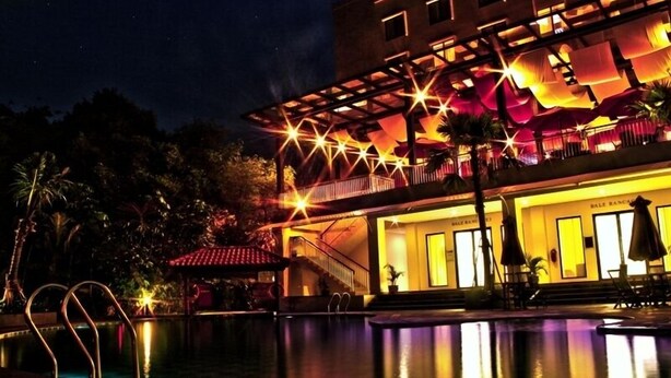 A hotel with a pool, outdoor seating, and a well-lit facade at night. - Padjadjaran Suites Resort & Convention (Bogor)