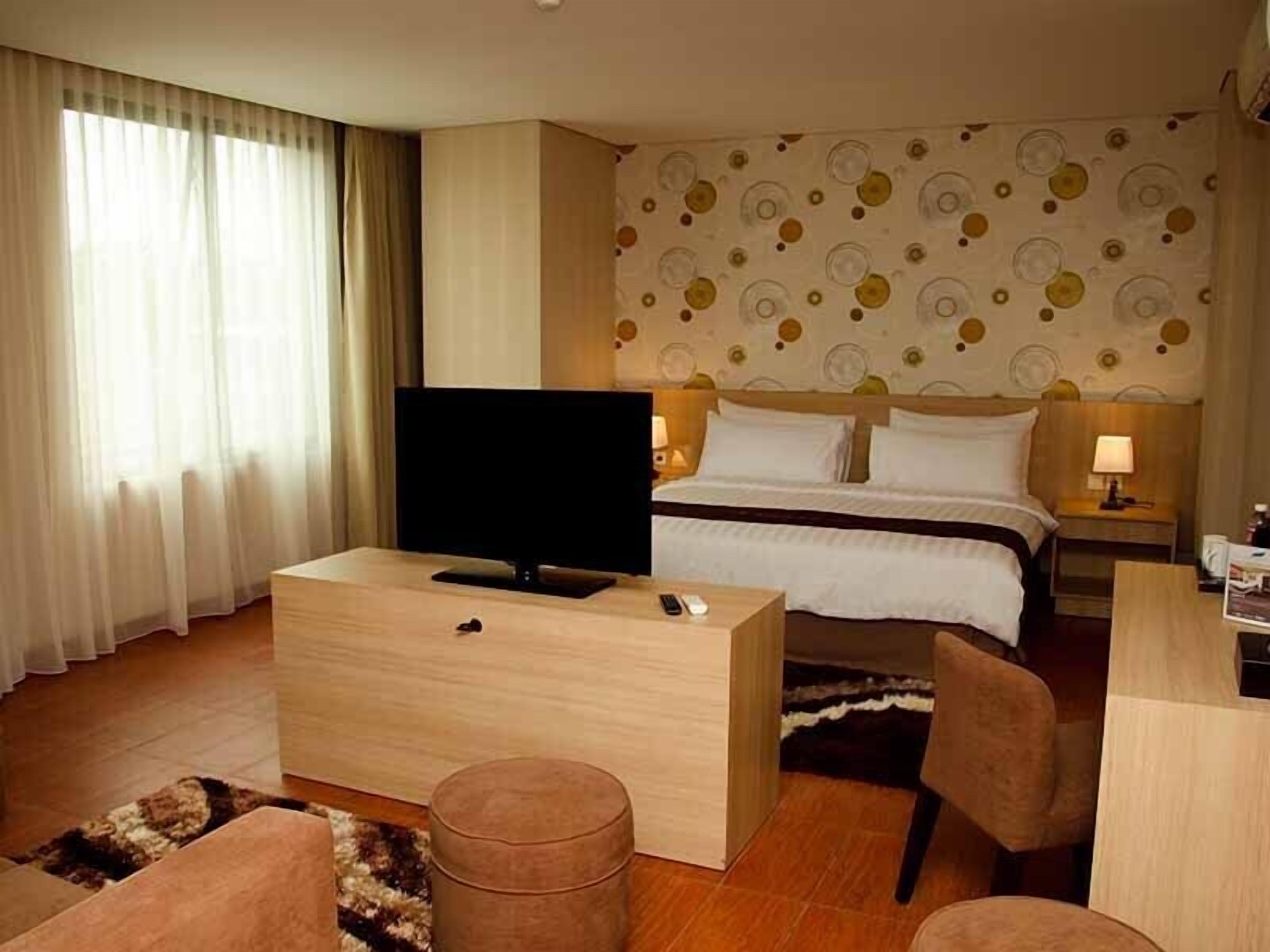 A hotel room with a bed, a TV, a desk, and a chair.