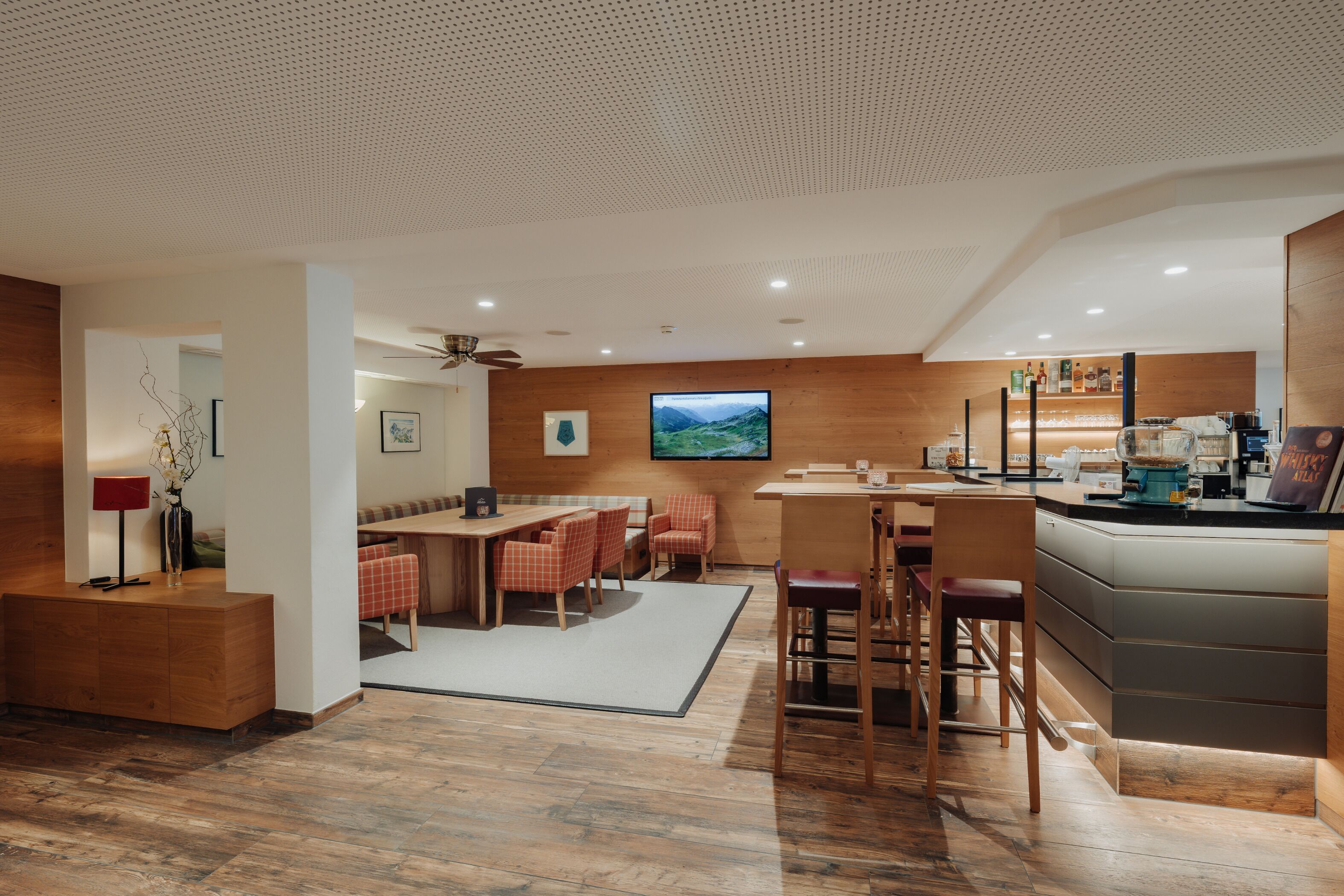 Un interior moderno con zona de comedor de madera, barra y asientos.