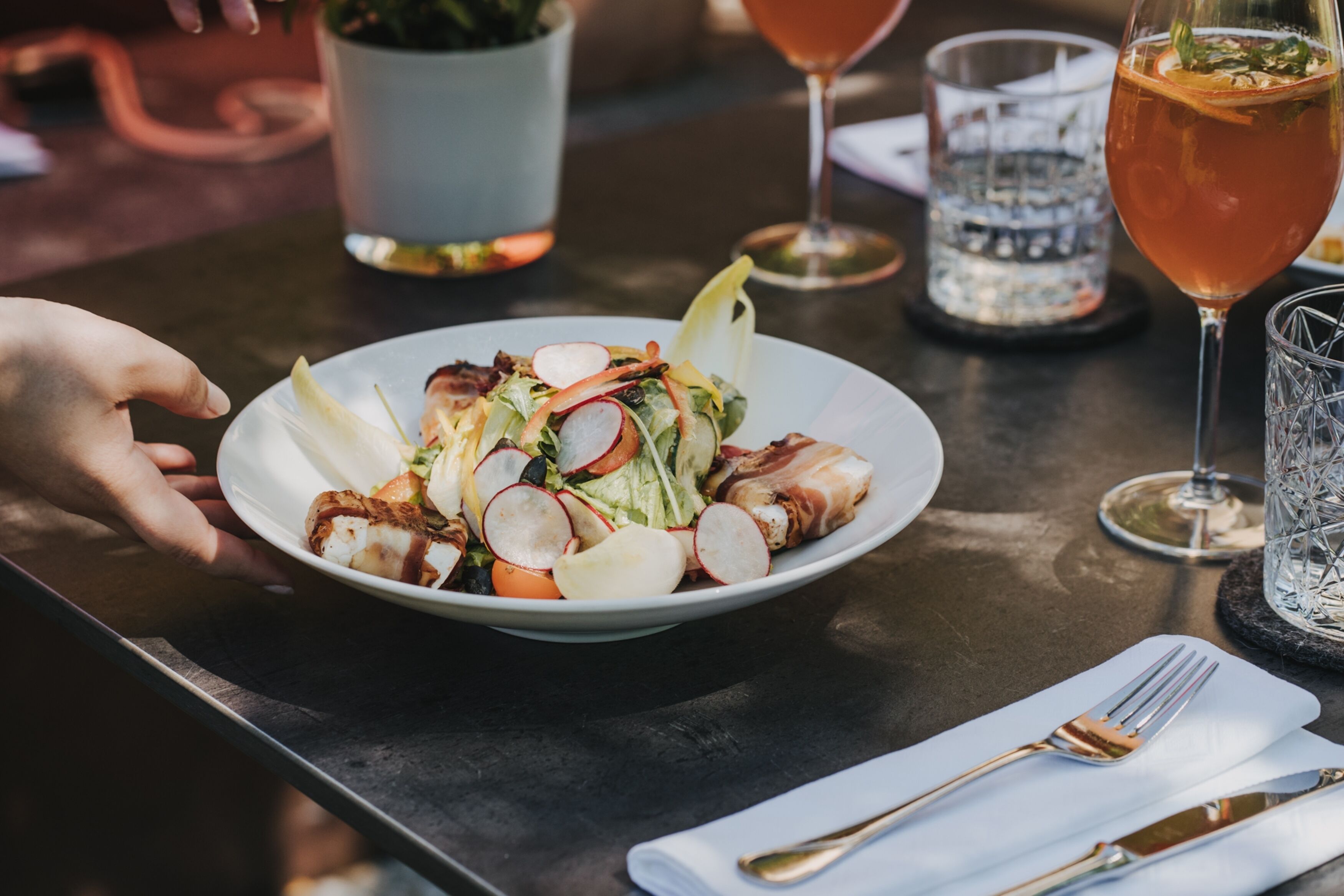 A dining table with a plate of food, a glass of drink, and cutlery.