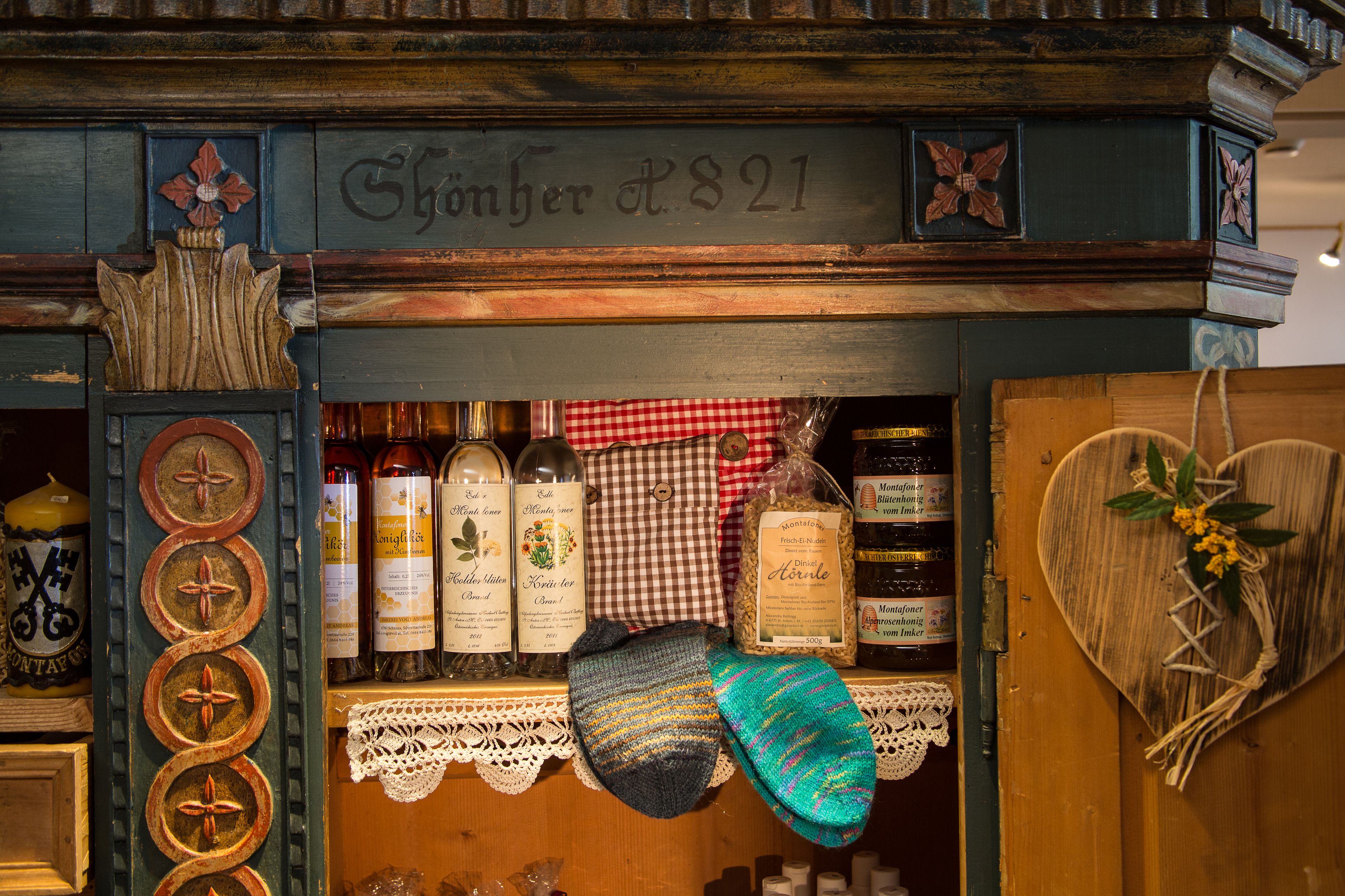 A vintage shop interior with wooden shelves displaying various items like bottles, a heart-shaped decoration, and a knitted sock.