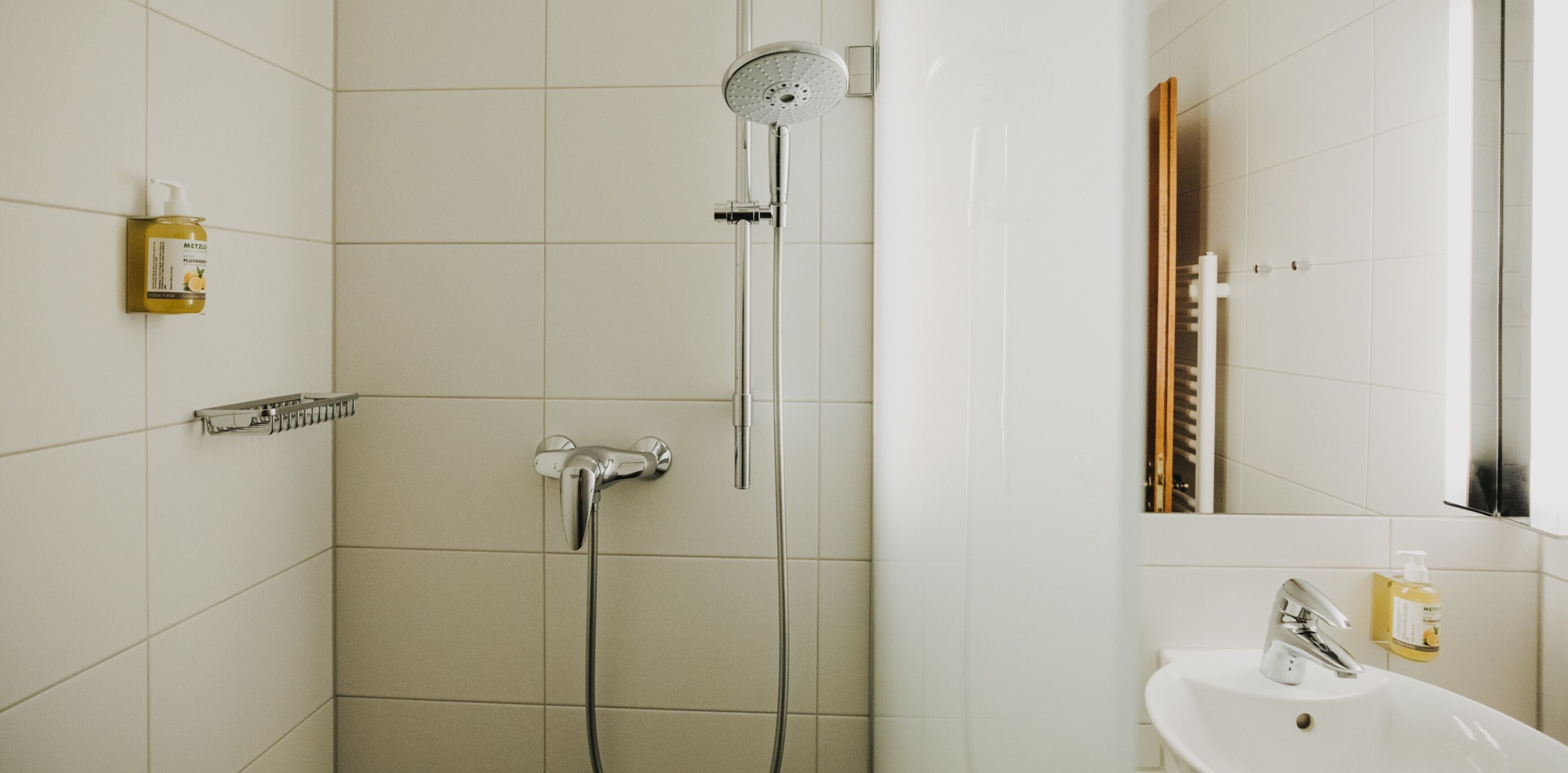 A modern bathroom with a shower, a sink, and a mirror.