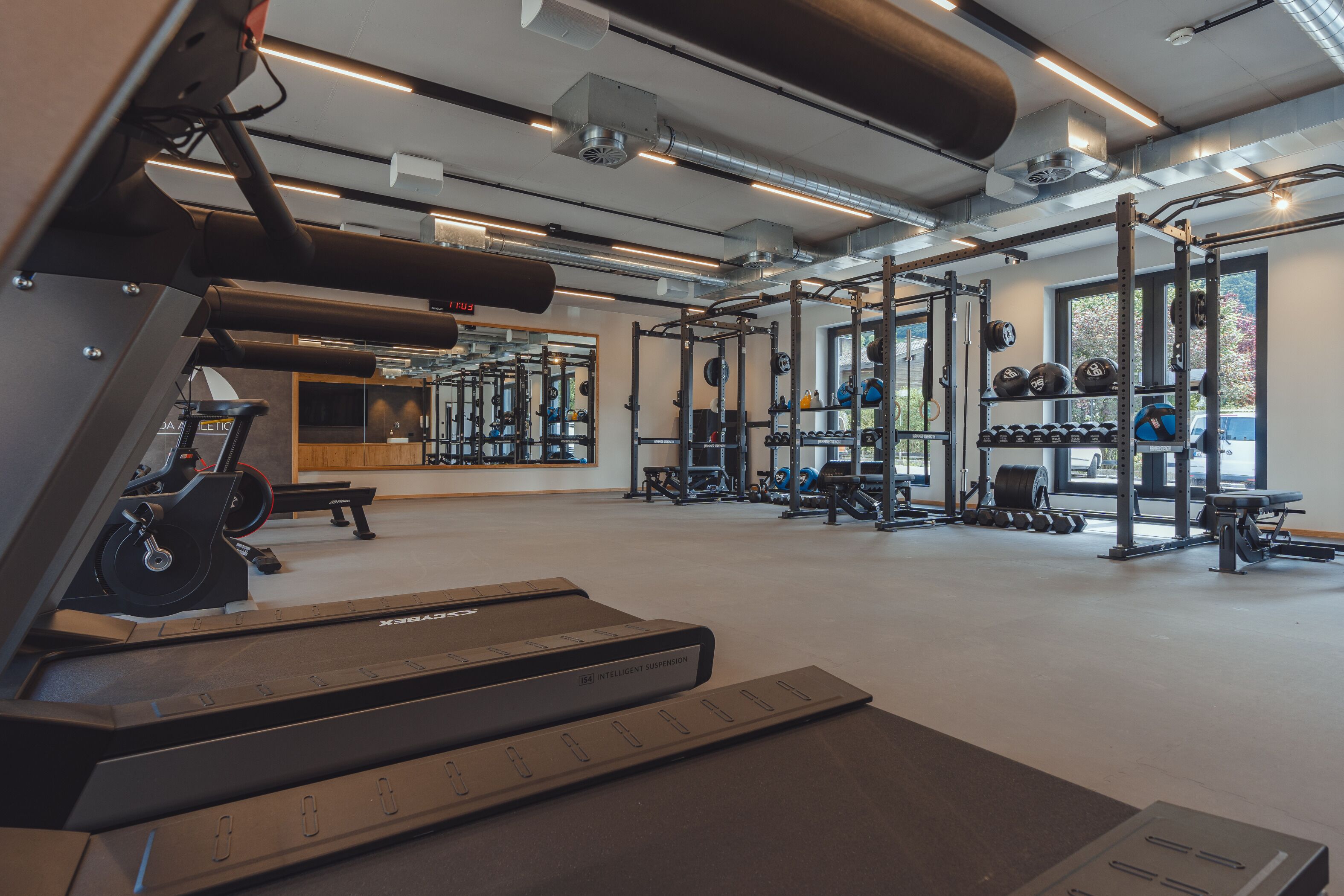 Un gimnasio con cintas de correr, equipo de levantamiento de pesas y espejos.