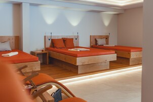 Habitación de hotel con tres camas de madera, cada una con ropa de cama naranja y cabeceros de madera.
