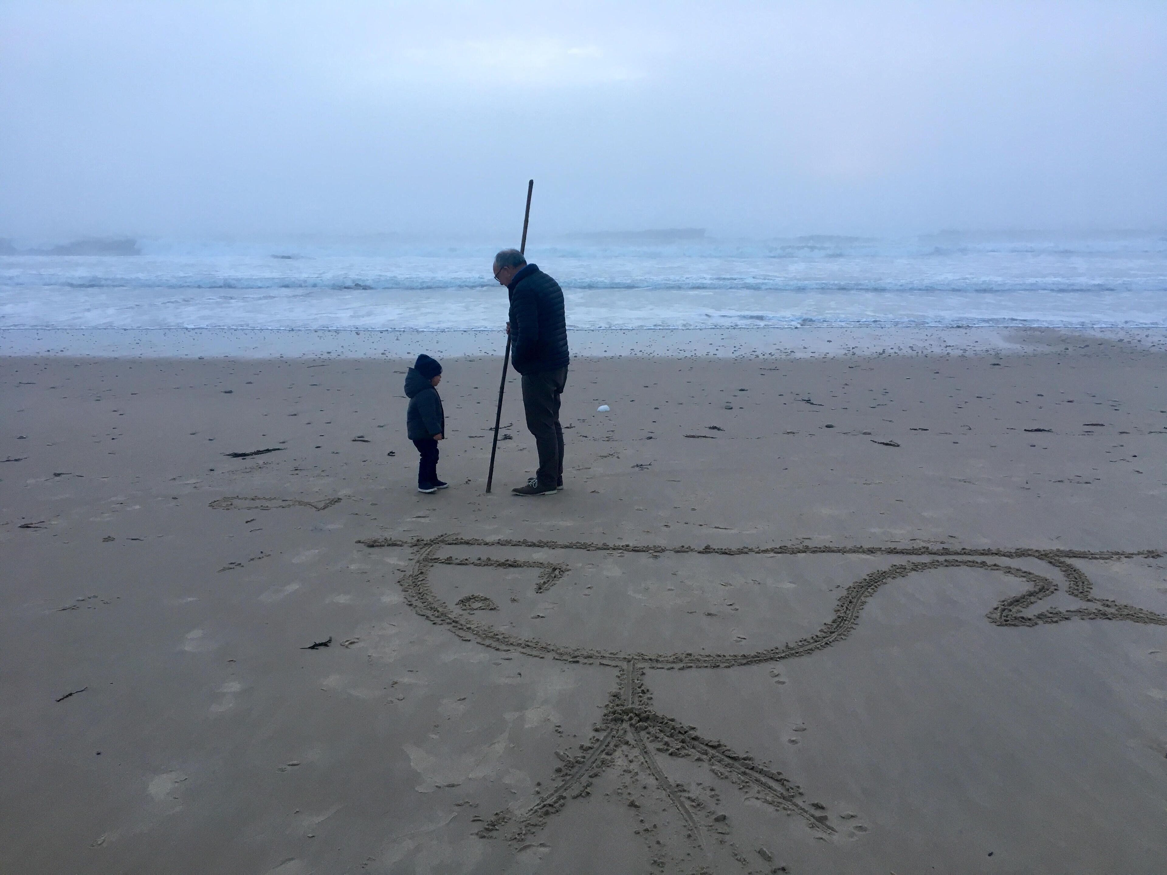 Una playa arenosa con huellas e ilustración de un pez.