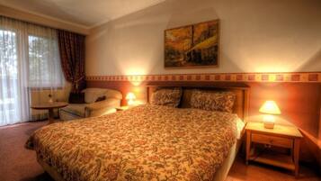 Habitación de hotel con una cama grande, una mesita, una silla y un cuadro en la pared.