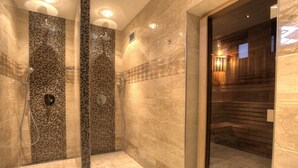 Een moderne badkamer met een mozaïekdouchewand, een aparte douchecel en een houten sauna.
