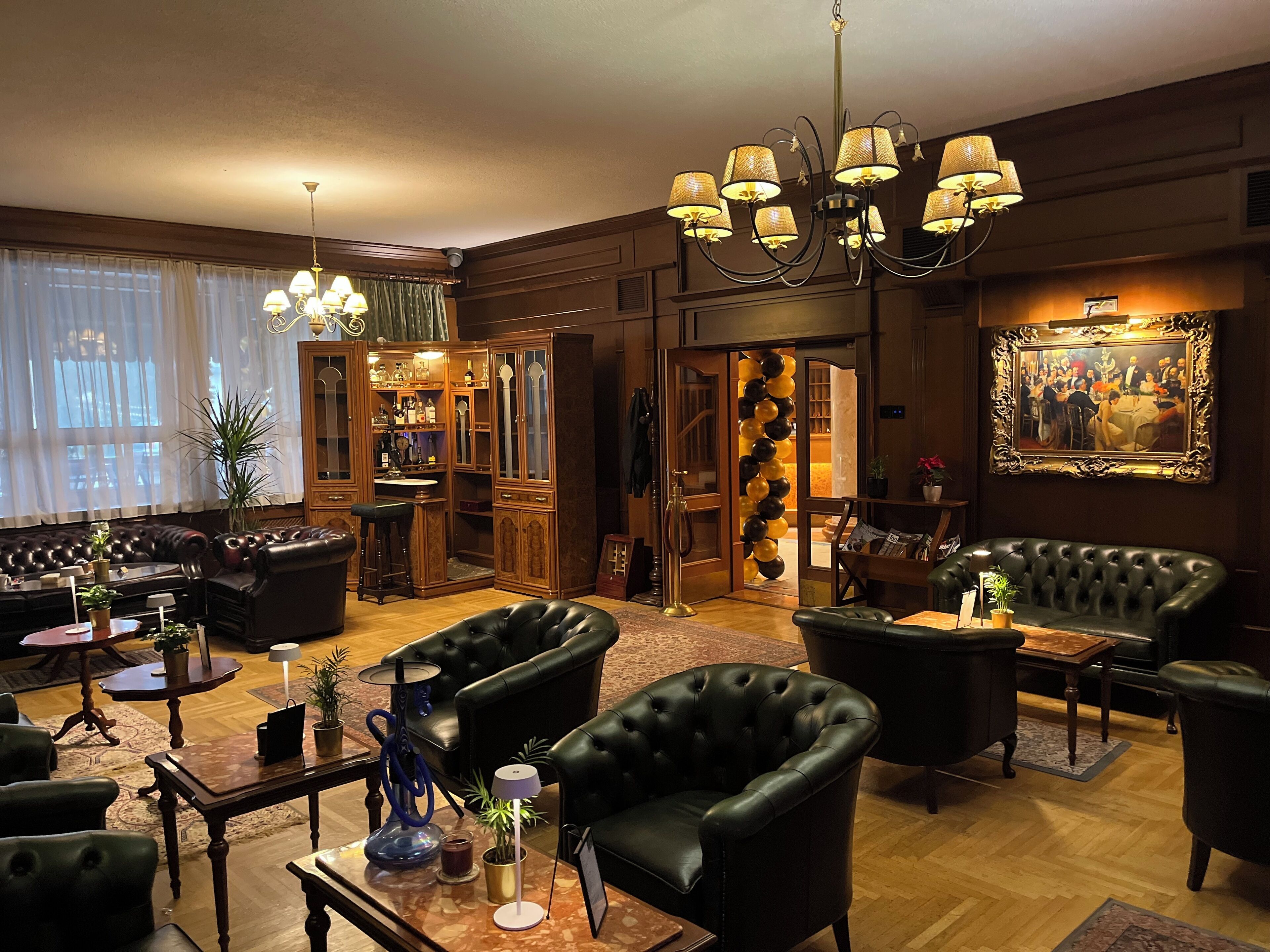 Een luxe loungeruimte met leren banken, een bar met houten kasten en een kroonluchter.