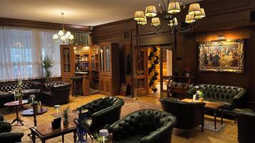 Een luxe loungeruimte met leren banken, een bar met houten kasten en een kroonluchter.