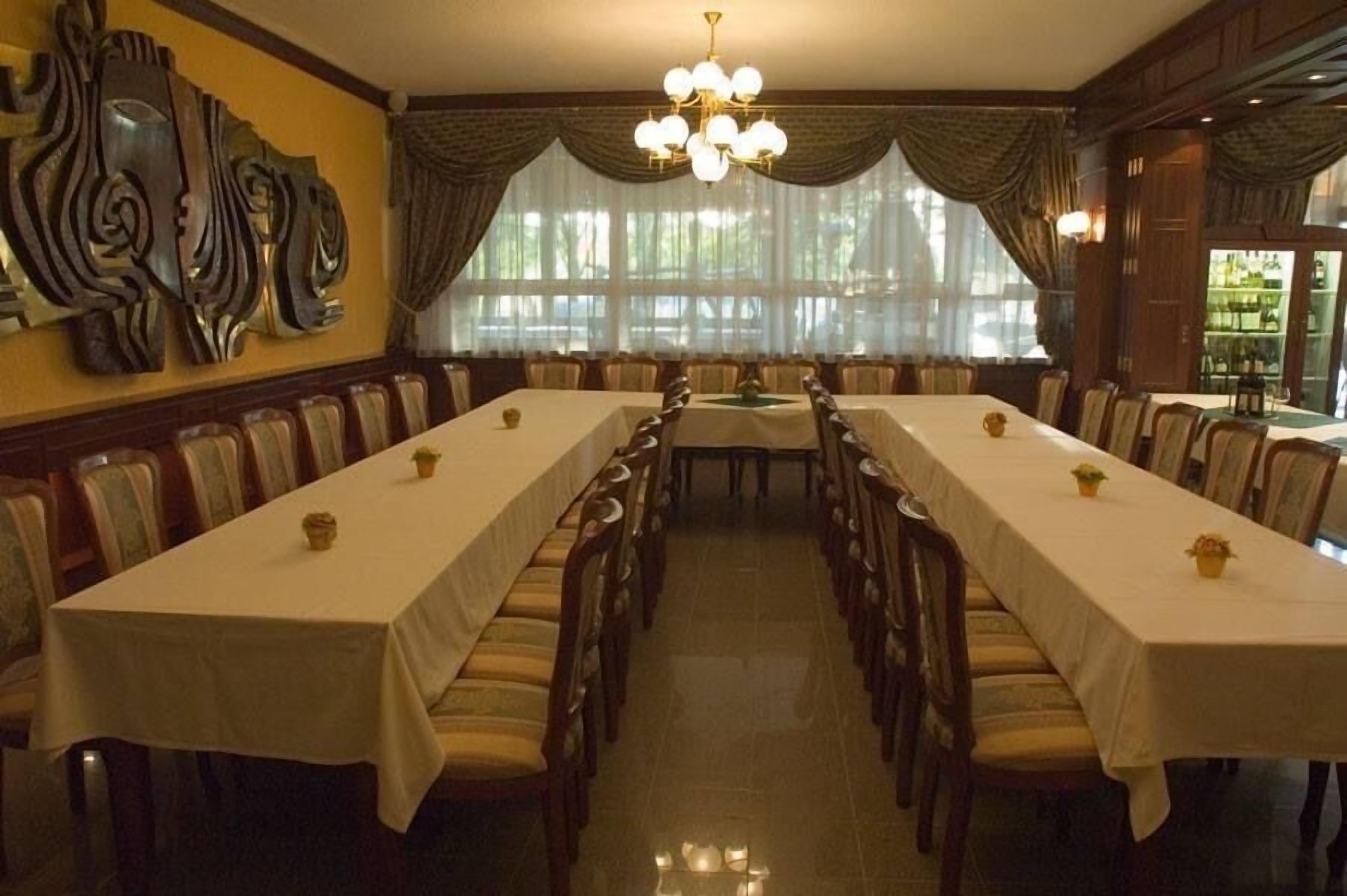 A formal dining room with long tables, chairs, and a chandelier.