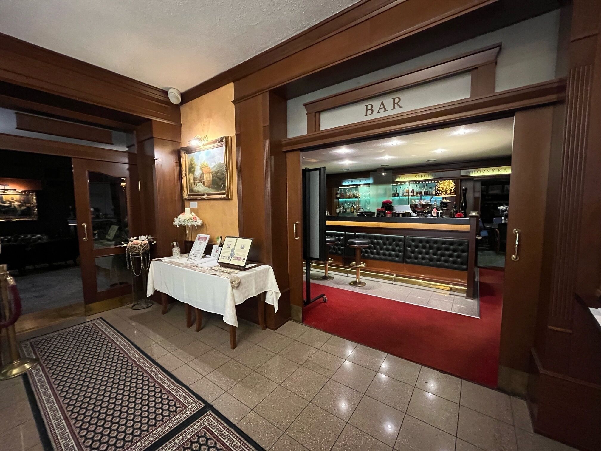 A bar area with a red carpet, wooden decor, and a framed picture on the wall.