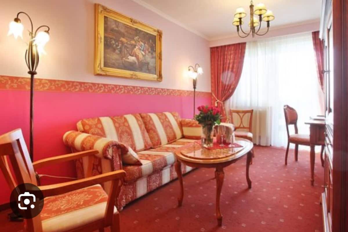 Une pièce avec un canapé, des fauteuils, une table et un tableau au mur.