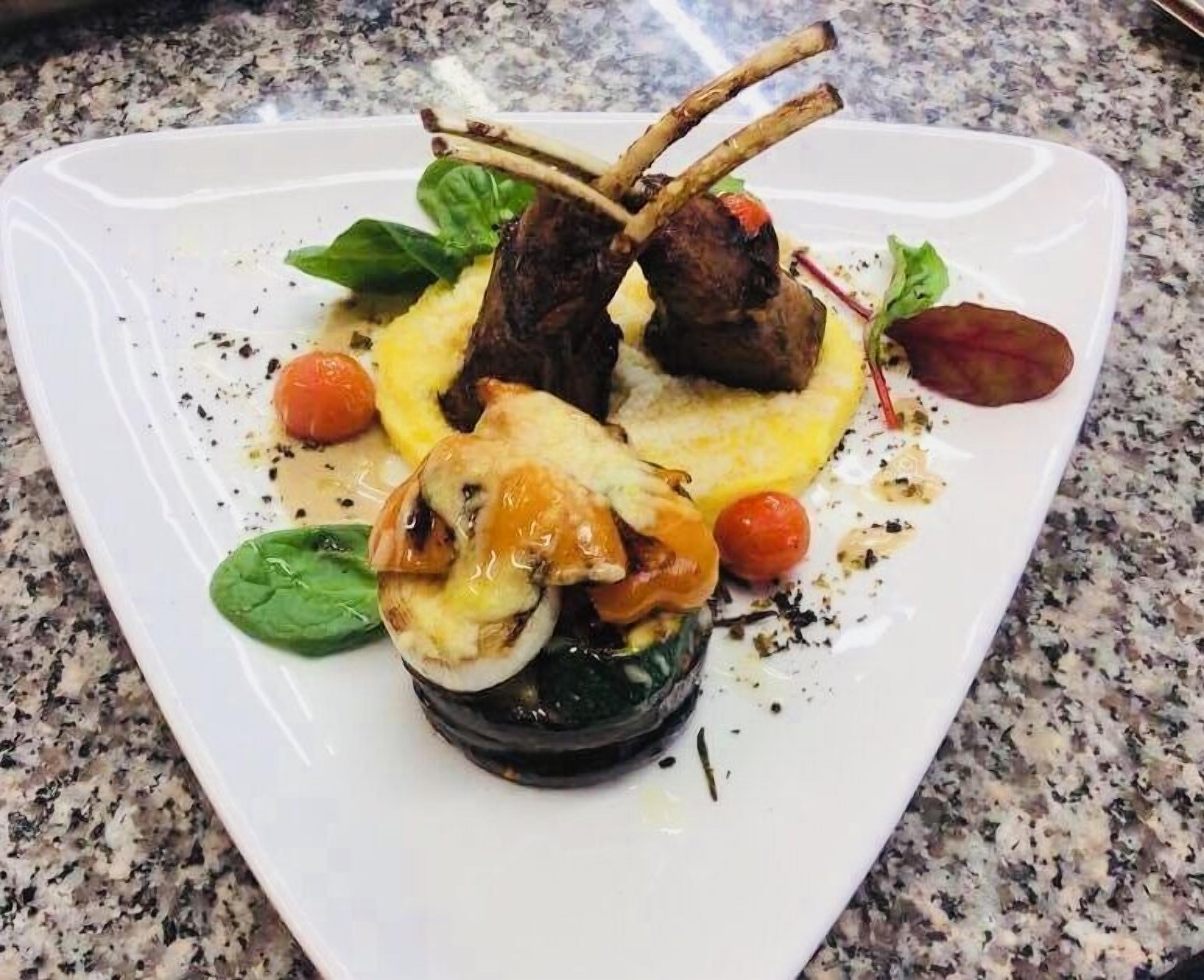 A square plate with a dish of meat, vegetables, and a garnish.