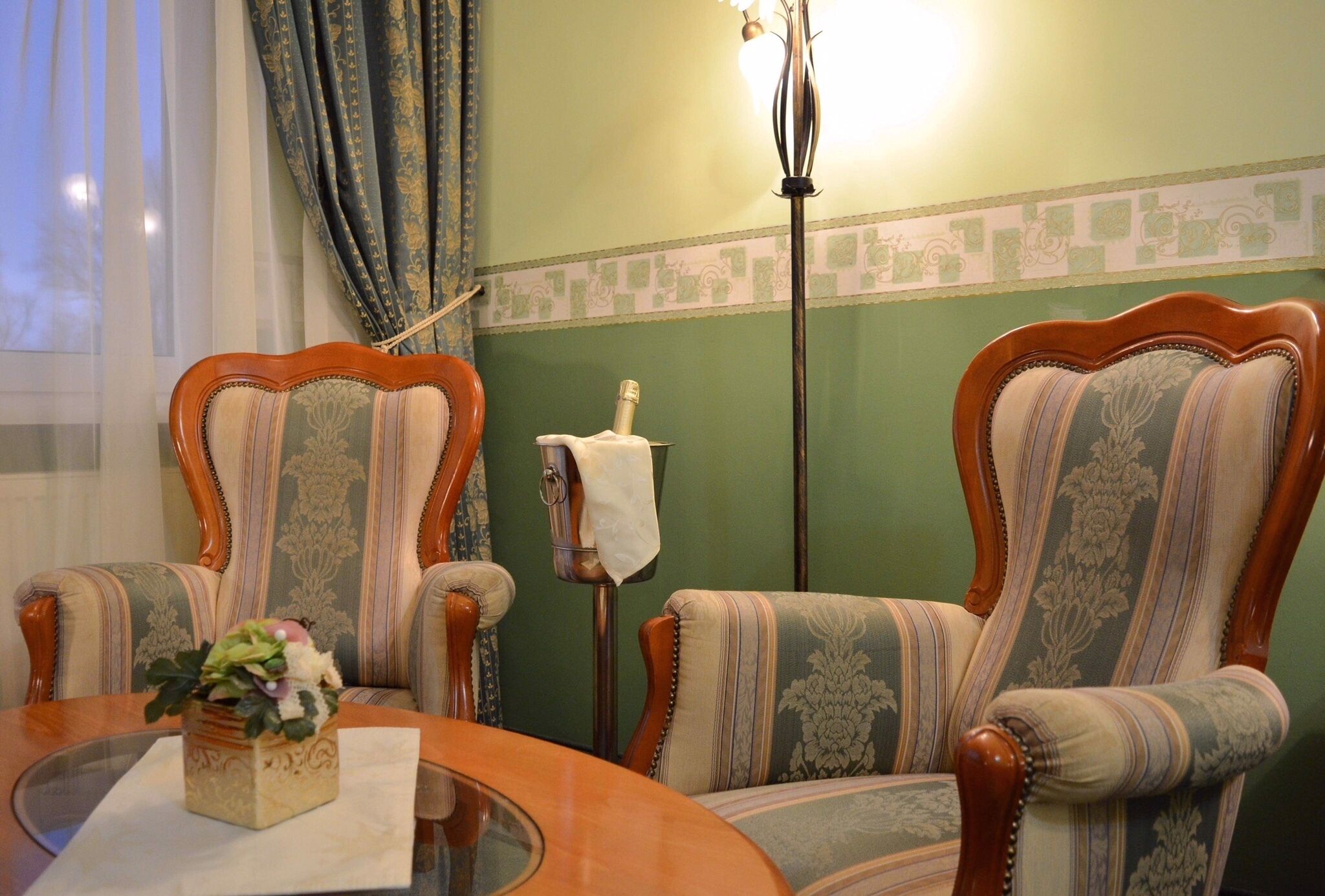 Une pièce comprenant deux fauteuils rembourrés aux motifs rayés, une table en bois avec un plateau en verre et un vase décoratif orné de fleurs.