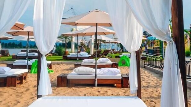 Een strandlounge met witte zonnedaken en ligbedden.