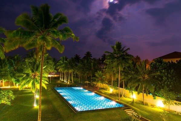 A nighttime view of a swimming pool surrounded by palm trees and well-lit pathways. - Taprobana Wadduwa by Asia Leisure (Wadduwa)