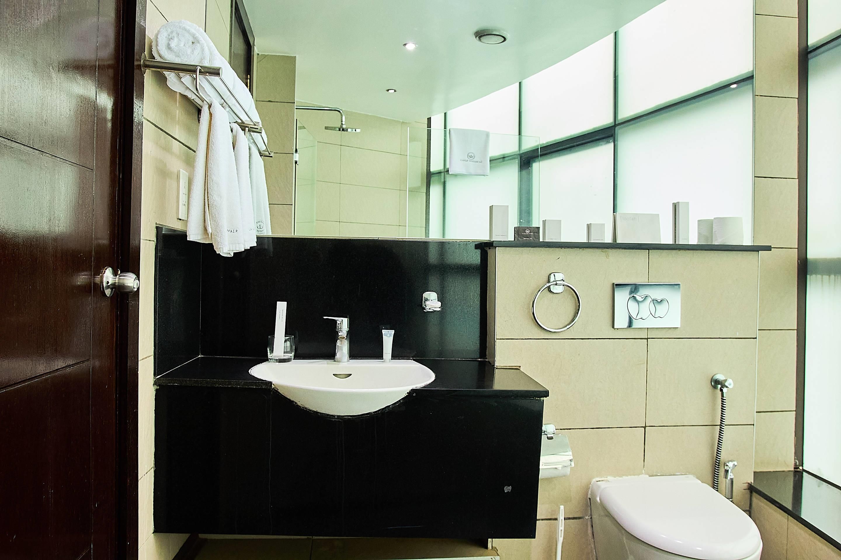 A modern bathroom with a black sink, a toilet, and a glass shower enclosure.