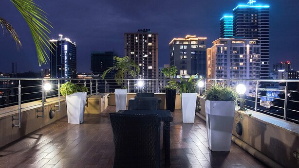 A rooftop terrace with outdoor furniture, potted plants, and a city skyline at dusk. - La Maison Royale (Nairobi)