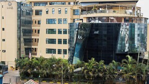 A multi-story building with a modern glass facade, balconies, and flags. - La Maison Royale (Nairobi)