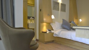 A modern hotel room with a bed, bedside lamps, a nightstand, and a chair. - La Maison Royale (Nairobi)