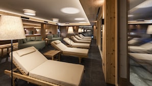 A spa area with multiple sun loungers, a seating area with cushions, and wooden accents. - Natur Resort RISSBACHER (Stumm)
