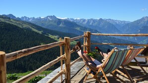 A wooden deck with a wooden railing overlooking a mountainous landscape. - Natur Resort RISSBACHER (Stumm)