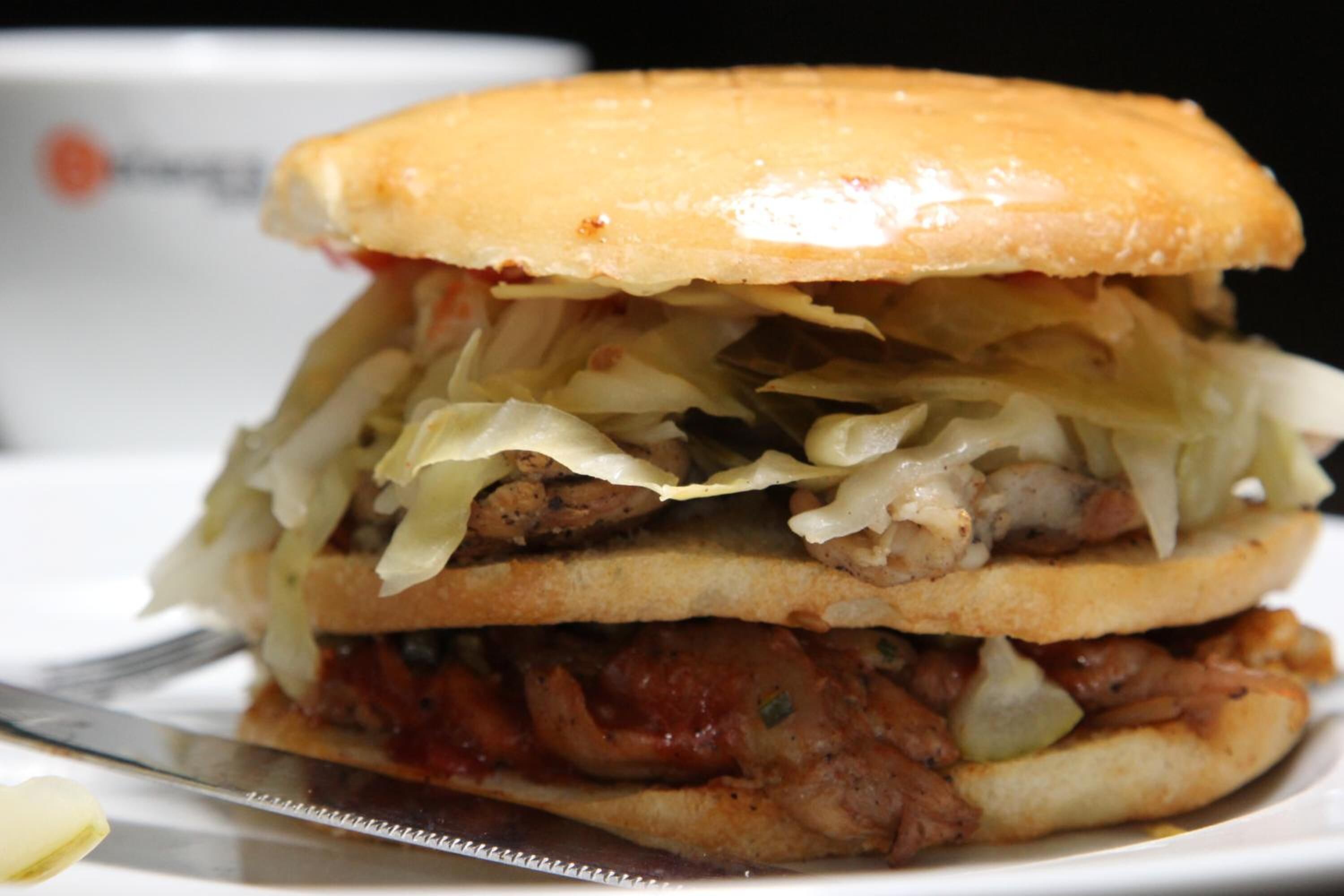 A sandwich with a bun, meat, and sauerkraut.