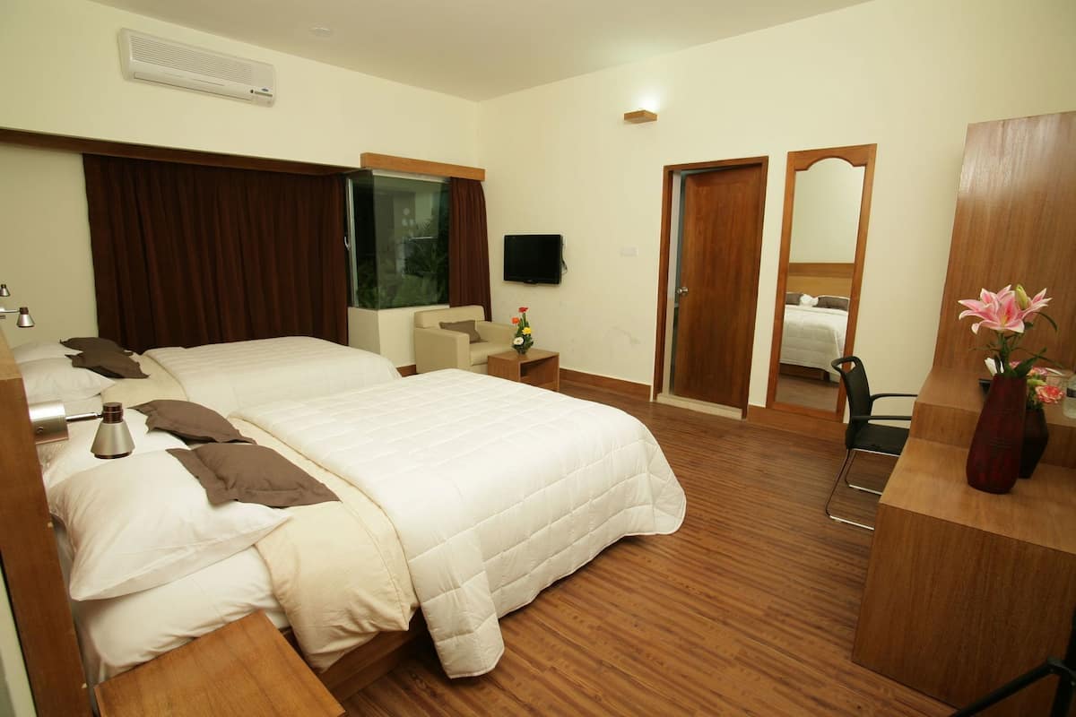 Una habitación de hotel con una cama grande, mesitas de noche, un escritorio, un espejo y una televisión.