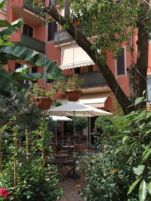 An outdoor patio area with a table and chairs, surrounded by potted plants and a hanging planter. - Residence Gloria (Montecatini Terme)