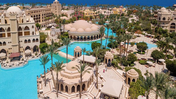 Un complexe hôtelier doté de plusieurs piscines, de palmiers et d’une architecture traditionnelle.