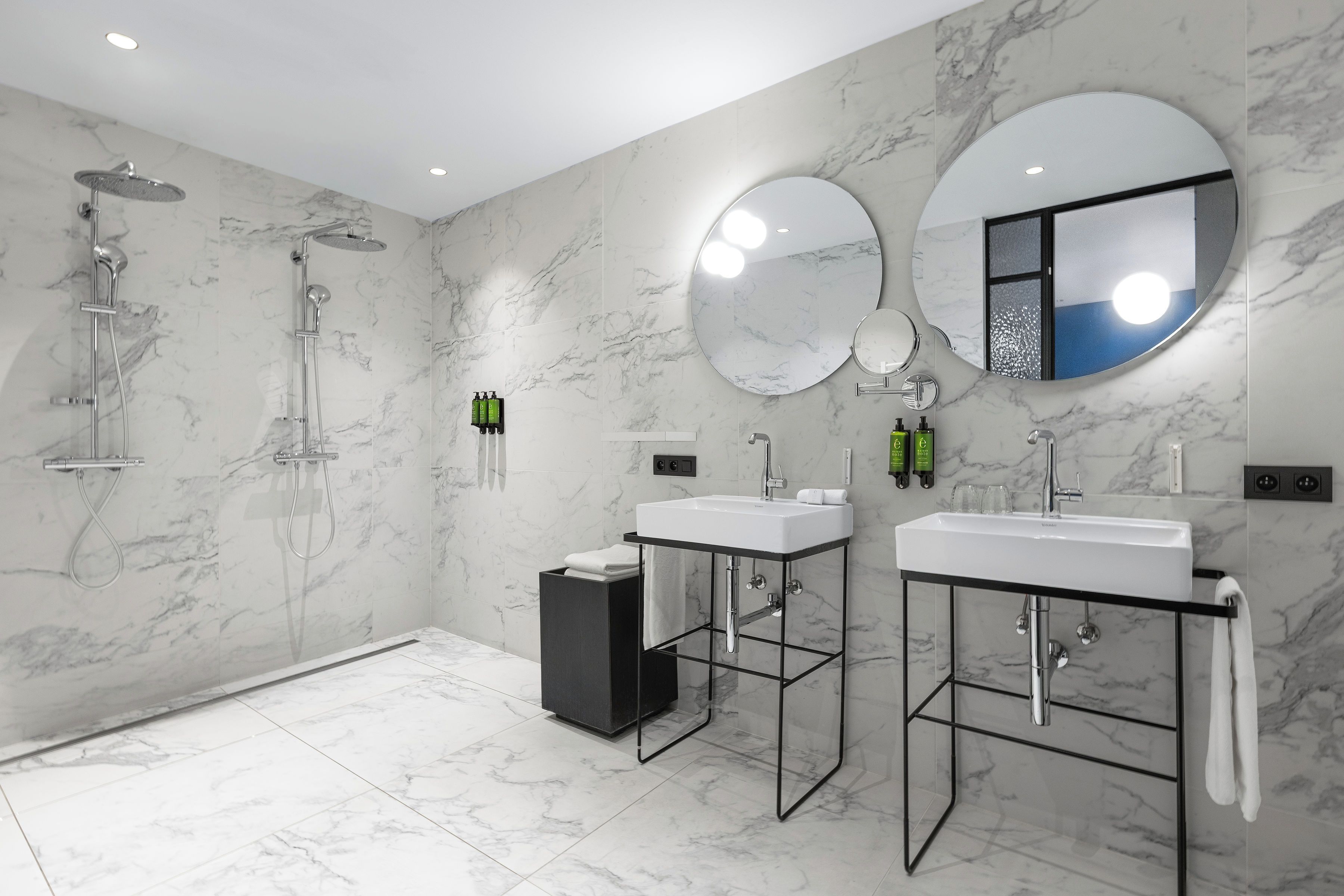 A modern bathroom with a shower, two sinks, and a mirror.