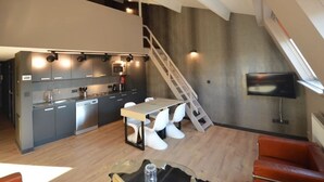 Een moderne keuken met een eethoek, een trap en een aan de muur bevestigde televisie.