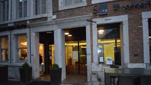 Een hotelentree met een glazen deur, een bord boven de deur en een gevel van baksteen.