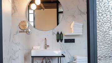 A modern bathroom with a marble sink, a round mirror, and a black vanity.