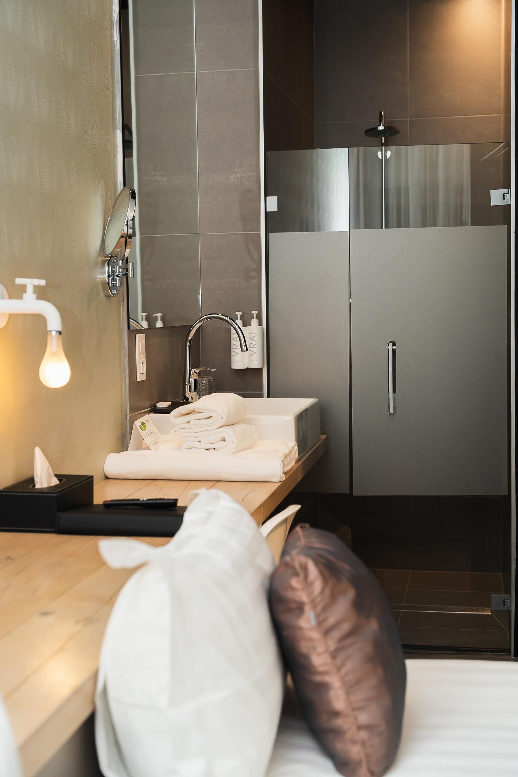 Une salle de bain moderne équipée d’un lavabo, d’un miroir, d’un porte-serviettes et d’un espace douche.