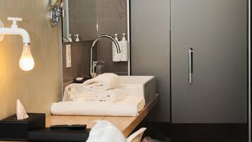 Une salle de bain moderne équipée d’un lavabo, d’un miroir, d’un porte-serviettes et d’un espace douche.